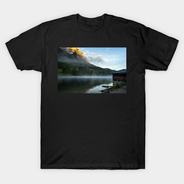 Misty Lake Portrait wide angle with boathouse. Amazing shot of a wooden house in the Ferchensee lake in Bavaria, Germany, in front of a mountain belonging to the Alps. Scenic foggy morning scenery at sunrise. T-Shirt by EviRadauscher